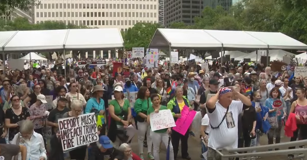 Massive crowd of people in a large squre with protest signs
