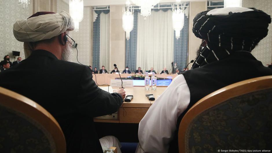 Zwei Taliban-Vertreter sitzen an einem großen Runden Tisch auf einer Konferenz in Moskau im Oktober 2021