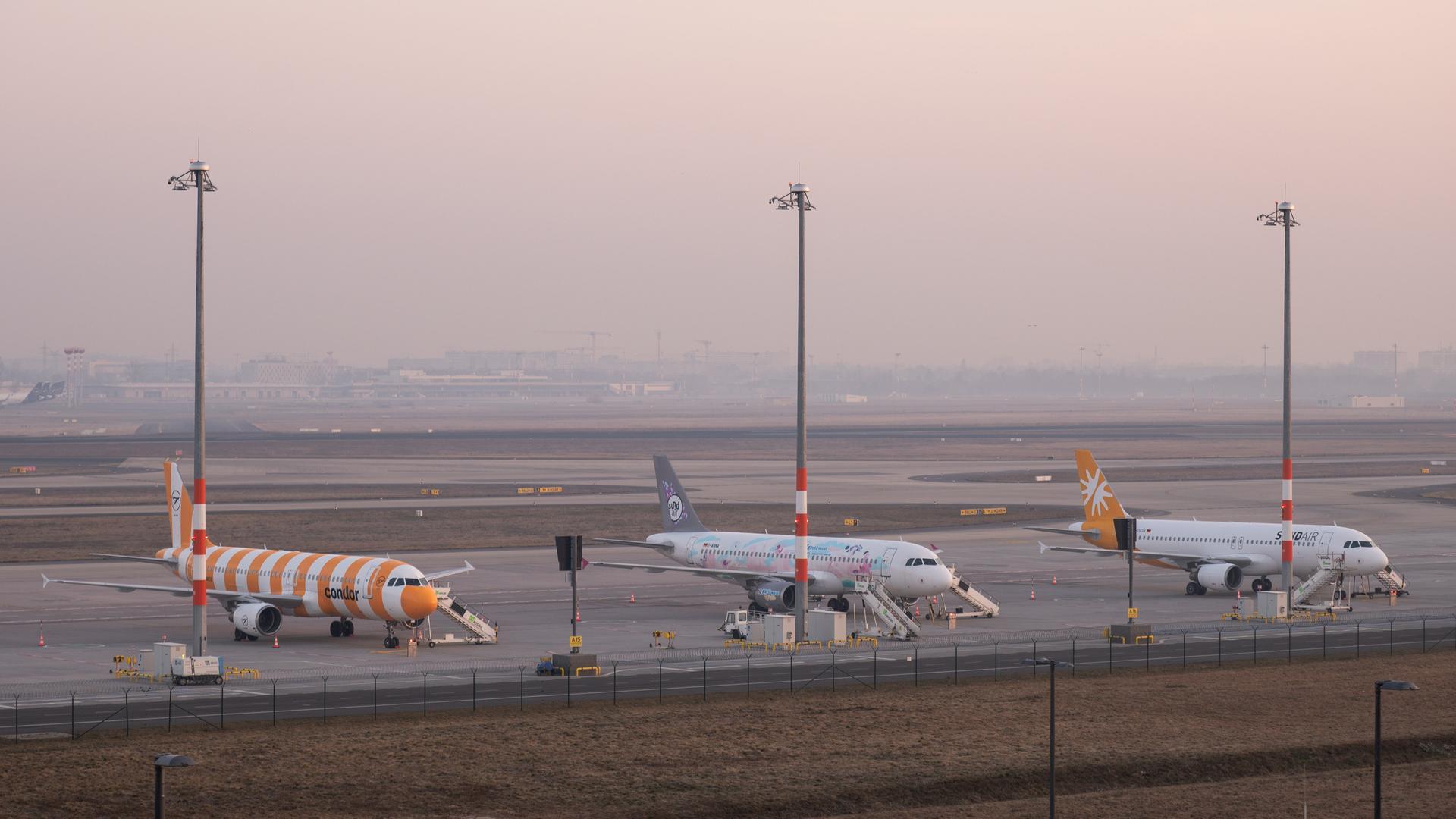 Maschinen der Fluggesellschaften Sund Air und Condor stehen am Flughafen Berlin Brandenburg BER auf dem Rollfeld. 