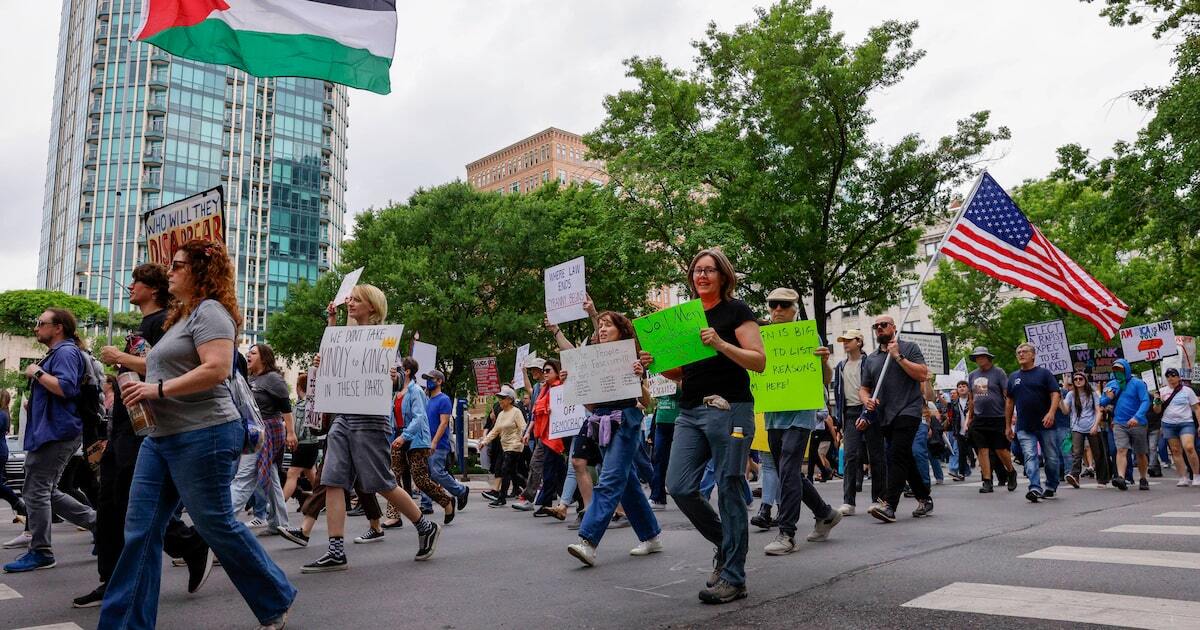 People carry signs and flags as they march during a 50501 protest against President Donald Trump on Saturday, April 19, 2025, in downtown Fort Worth.