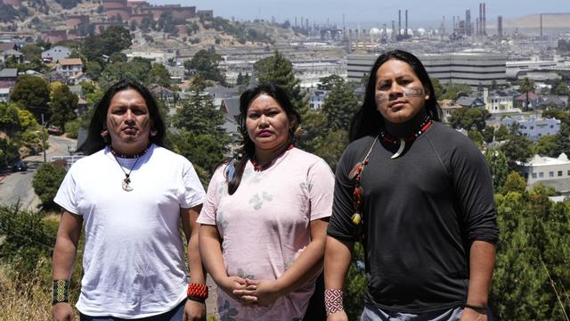 Juan Bay, president of the Waorani people of Ecuador, from left, Jhajayra Machoa Mendúa and Nadino Calapucha, a spokesperson for the Kichwa Pakkiru people, pose for a photograph as a Chevron refinery is visible in the background, June 19, 2025, in Richmond, Calif. (AP Photo/Godofredo A. Vásquez, File)