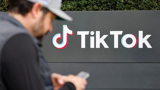 Un homme regarde son téléphone devant des bureaux de TikTok aux États-Unis.
