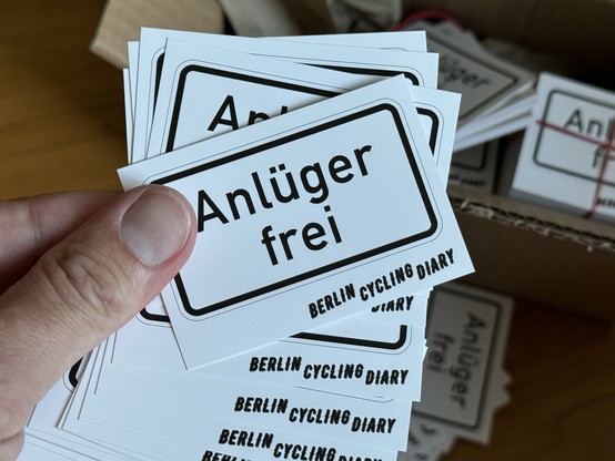 Hand die mehrere Sticker im Form eines Verkehrs Zusatzzeichens mit dem text 