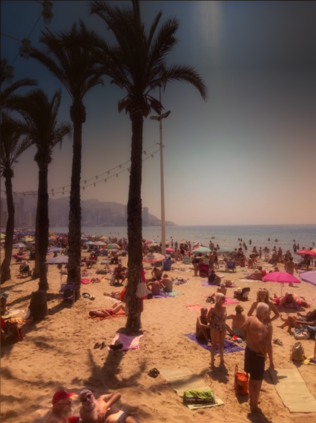 ein altes photo Sept. 2013, der Strand von Benidorm in warmen verwaschenen Farben, im Vordergrund eine Menge Badende, links eine Palmenreihe